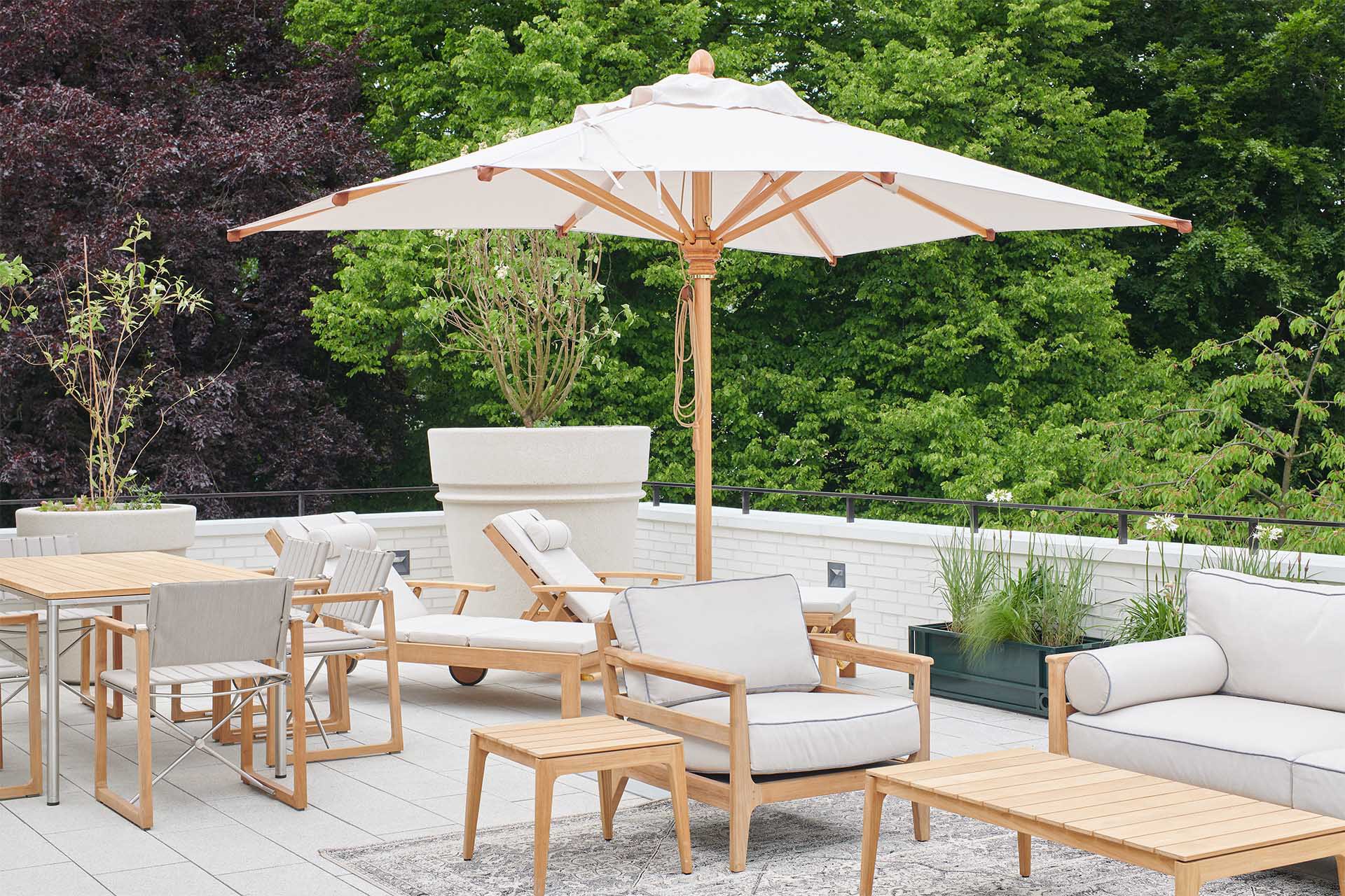 Roof terrace of the SOPHIE Penthouse with parasol, lounge furniture and a view of the greenery